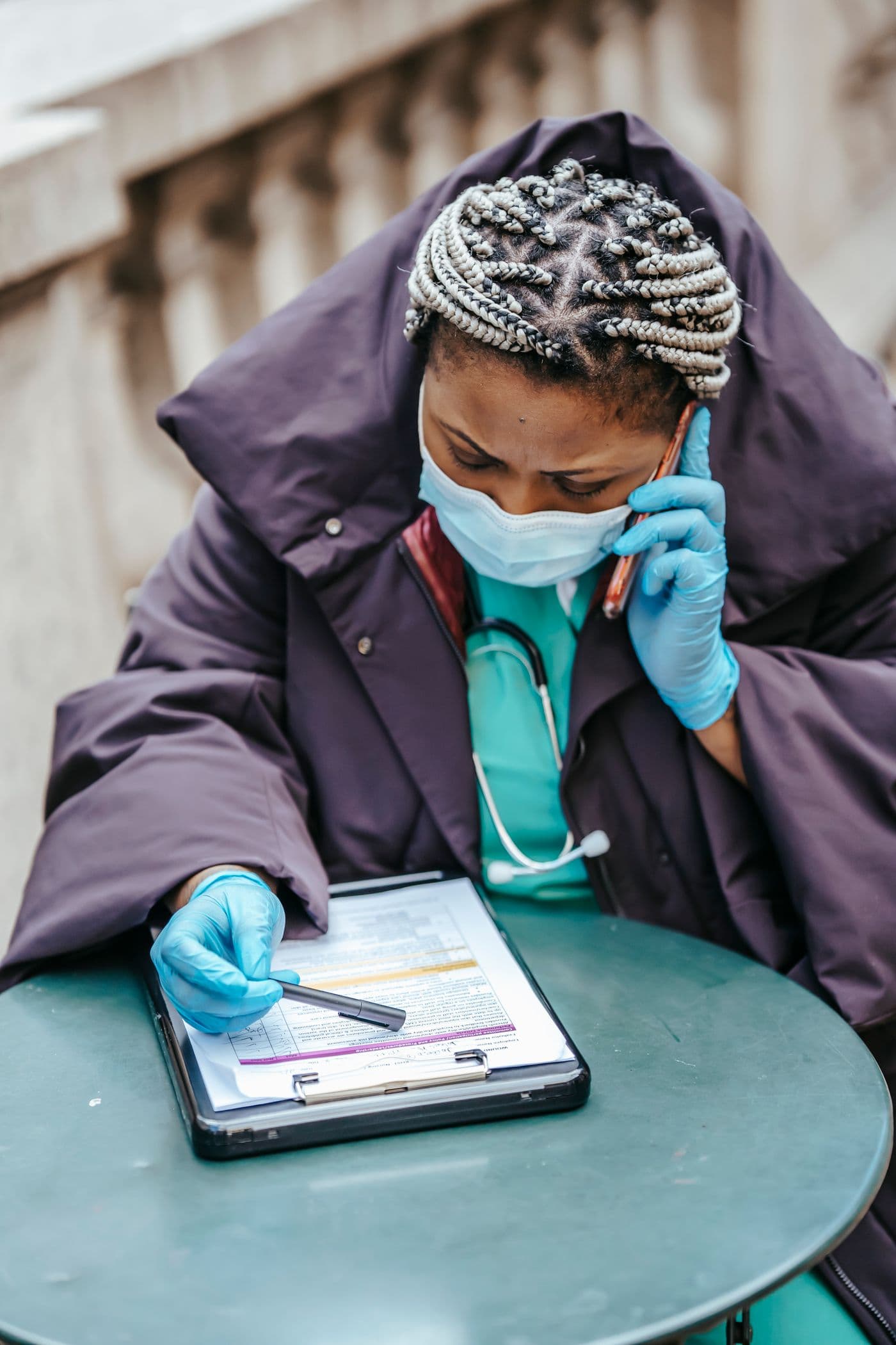healthcare worker outdoors speaking on a phone beside a clipboard